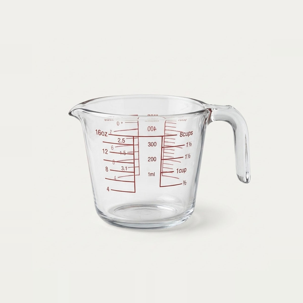 Clear glass measuring cup with red measurement markings and a curved handle, shown on a plain light background.