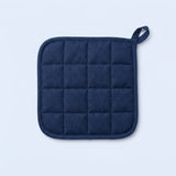 A navy blue quilted pot holder with a small loop handle, shown flat against a light blue background.