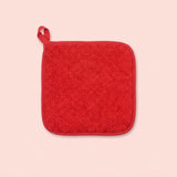 A square red terrycloth pot holder with a matching red fabric loop handle, shown flat against a solid pale pink background.
