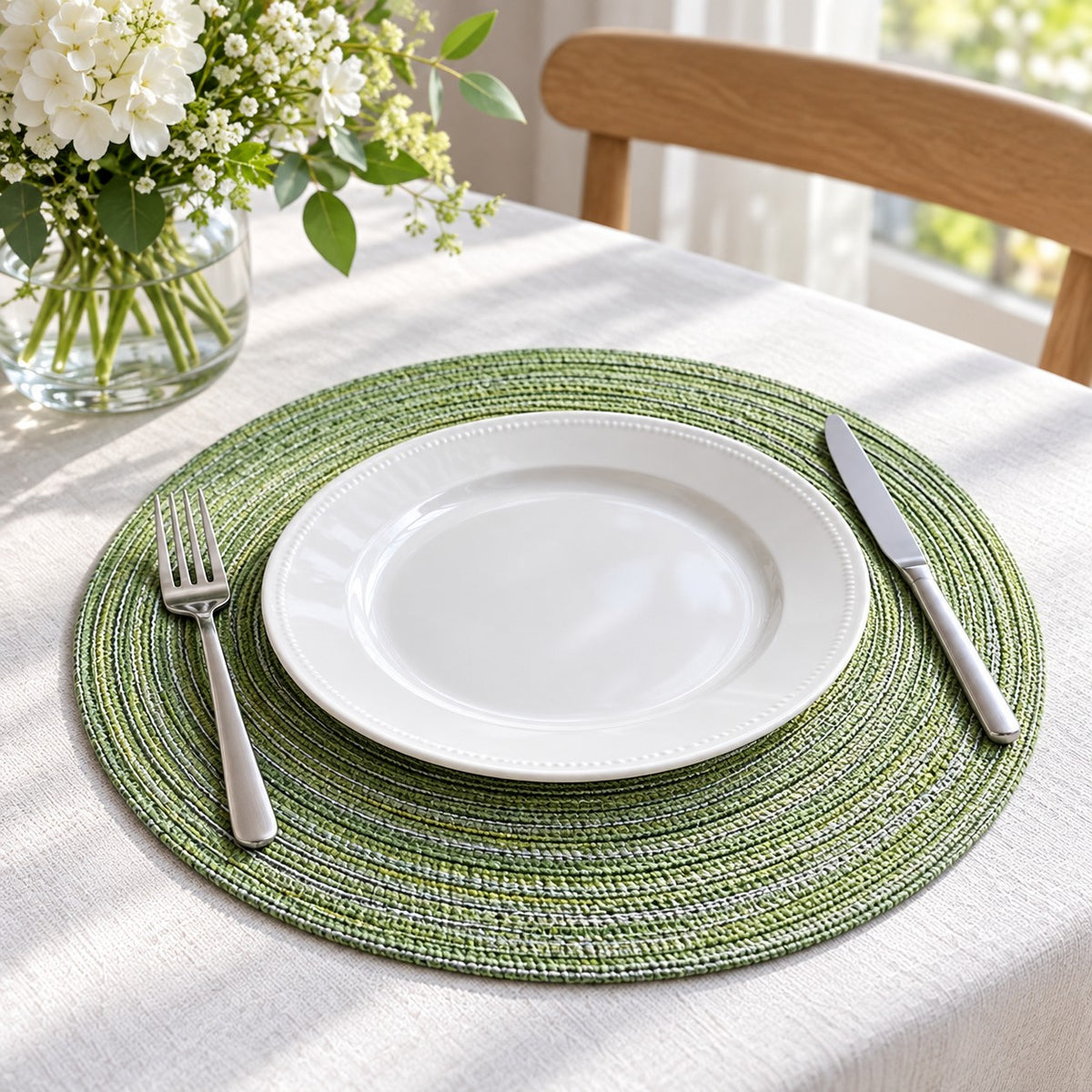 Green Round Woven Table Mat beneath a white plate on a bright dining table.