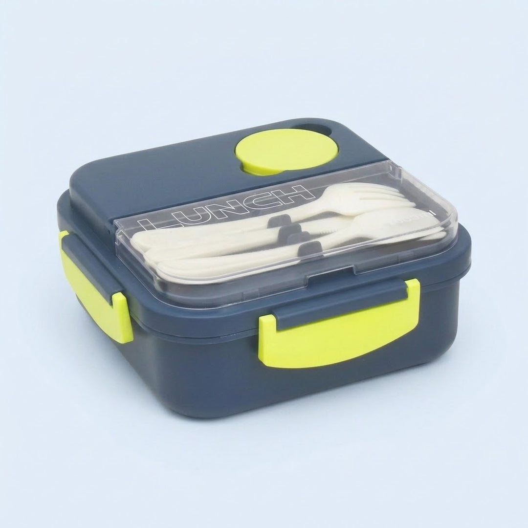 A navy blue lunch box with bright yellow accents, including a lid button, latch, and handle, containing white plastic cutlery under a clear lid. The lunch box is photographed on a light blue background.