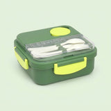 A square lunch box in dark green with bright yellow-green accents on the lid, handles, and side latches. The clear plastic lid is open, revealing white plastic utensils inside.