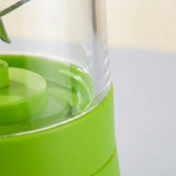 Close-up of a bright green and clear plastic container or blender base with a transparent cylindrical chamber.