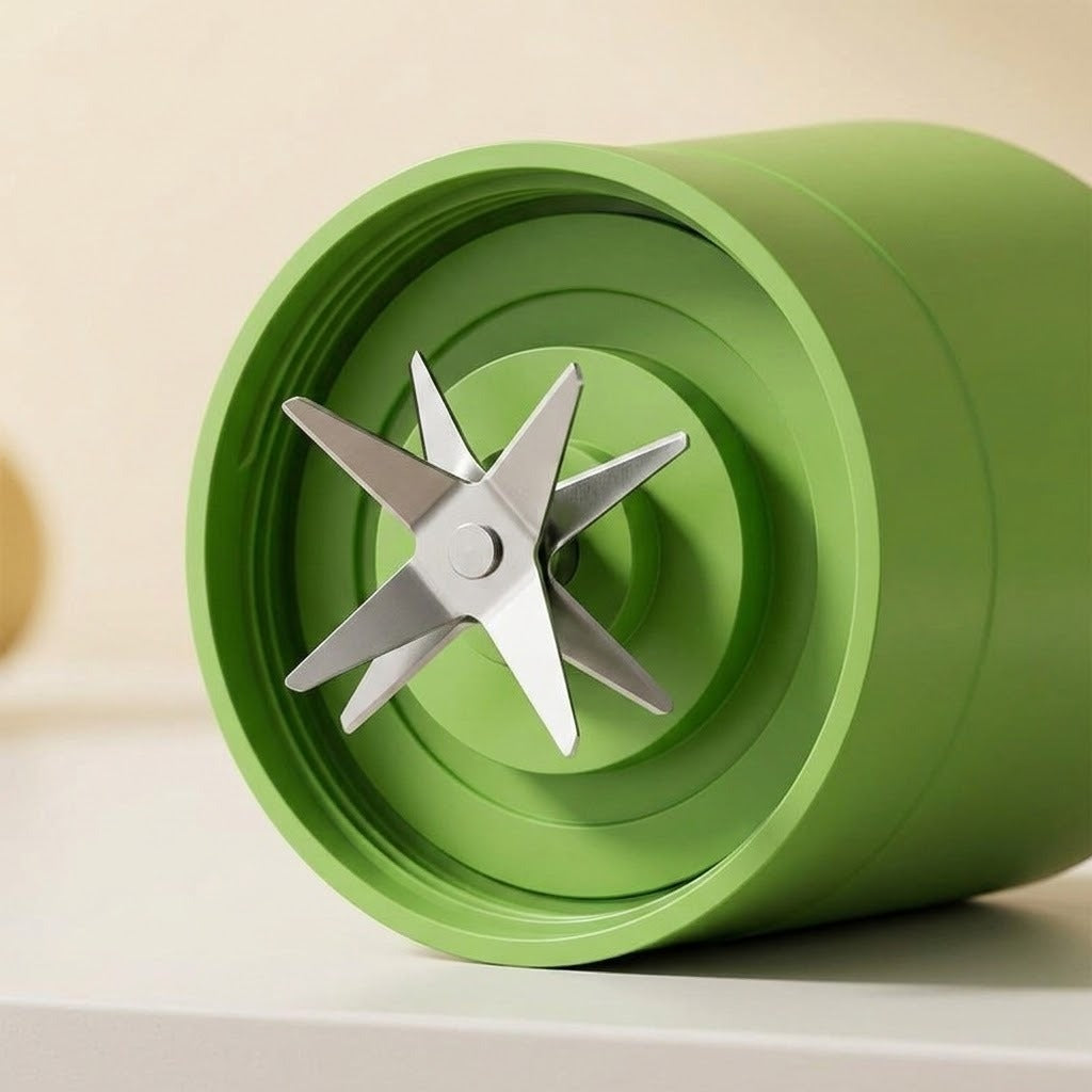 A close-up of a green blender jar lid or container component with a six-blade metal blade assembly resting inside, shown on a clean light beige background.