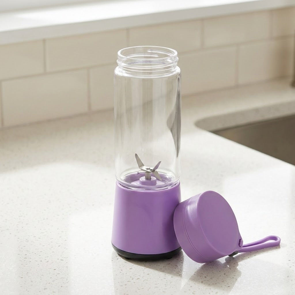 A purple and clear personal blender bottle with a matching purple lid and wrist strap, set on a light speckled kitchen countertop near a sink.