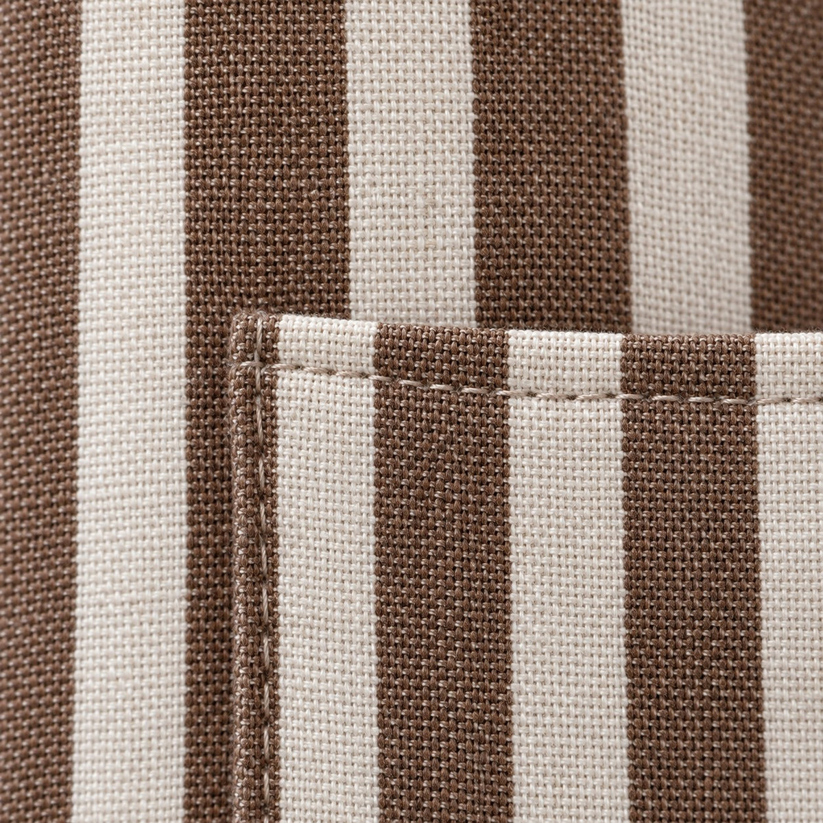 Close-up of the brown striped apron showing its woven linen-polyester texture and stitched pocket edge.