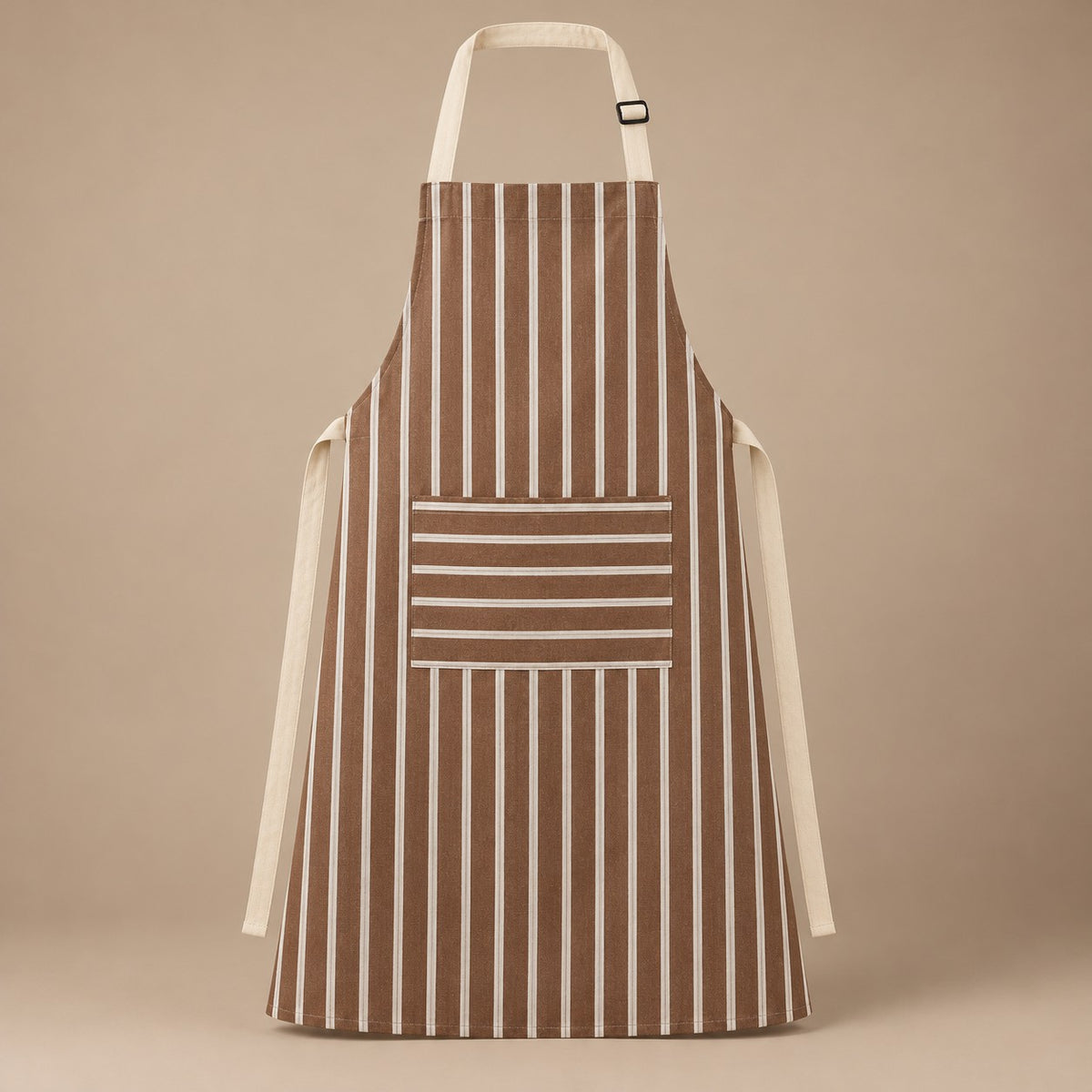 Brown striped kitchen apron with a horizontal pocket and adjustable straps on a warm studio backdrop.