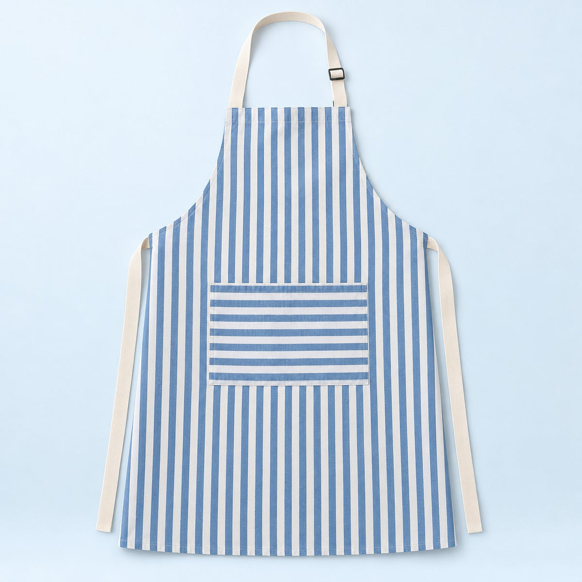 Blue striped kitchen apron with a horizontal pocket and adjustable straps on a pale blue studio backdrop.