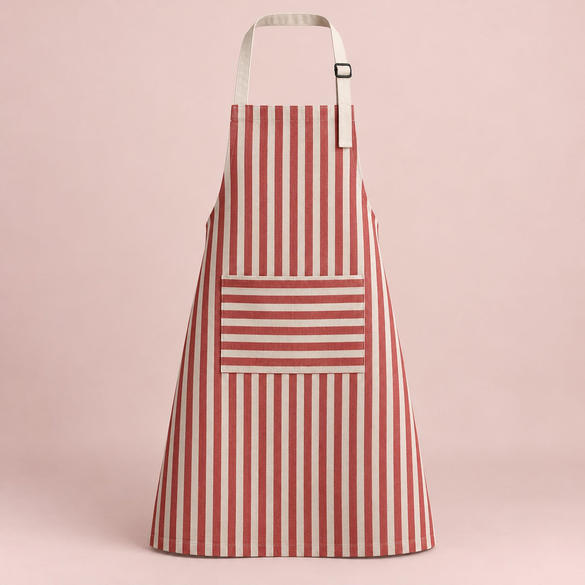 Red striped kitchen apron with a horizontal pocket and adjustable straps on a soft red studio backdrop.