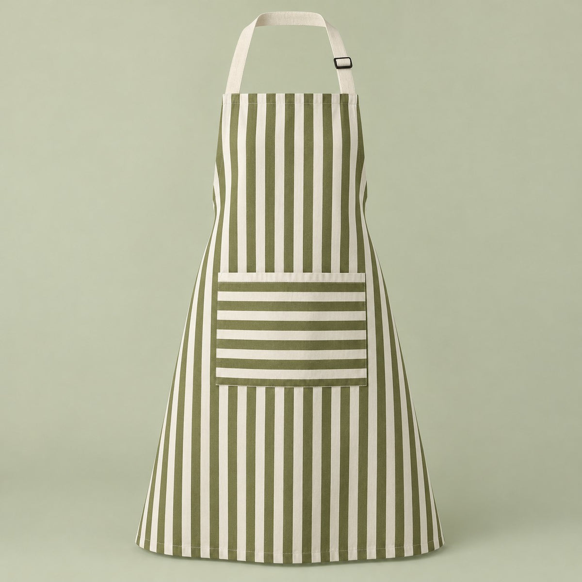Green striped kitchen apron with a horizontal pocket and adjustable straps on a pale green studio backdrop.