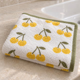 Cherry Print Cotton Washcloth folded on a bathroom counter, showing its cheerful pattern and terry texture.