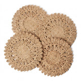 Four round woven seagrass coasters with a scalloped edge, arranged in a overlapping flat-lay composition on a solid white background.