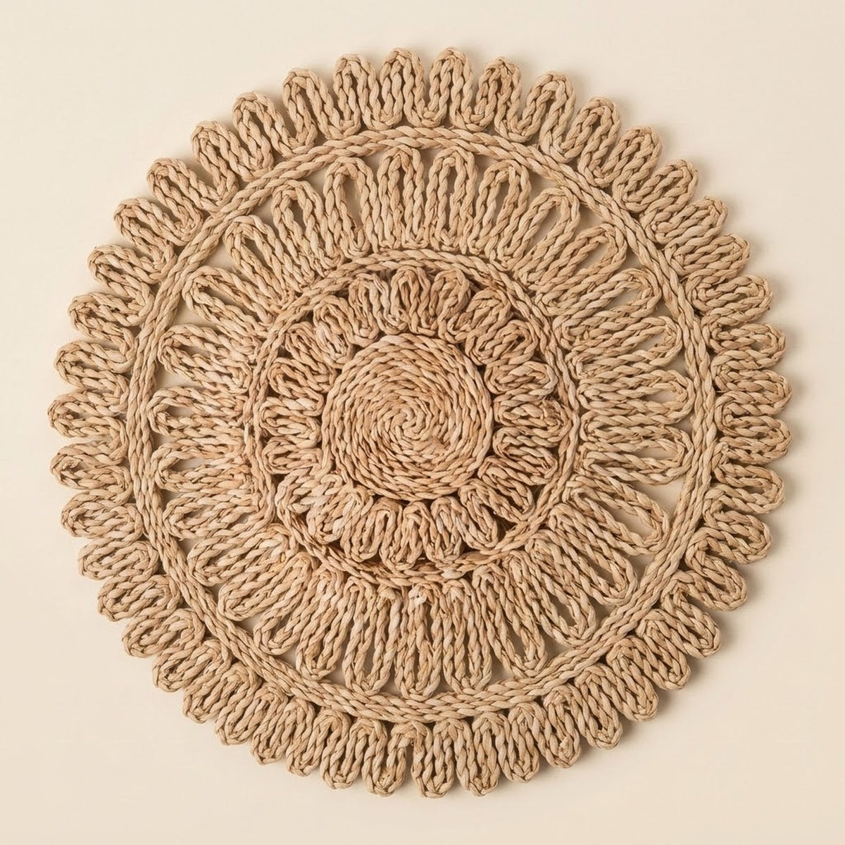 A round, handwoven jute wall hanging or decorative mat with concentric circular patterns and a scalloped outer edge, shown flat against a solid light beige background.