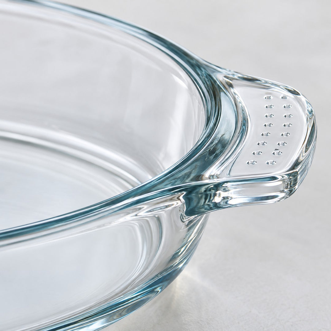 Macro detail of the clear baking dish's thick glass rim and dotted handle grip.