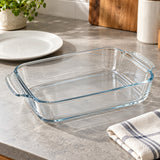Empty rectangular glass baking dish beside a dinner plate to show everyday scale.