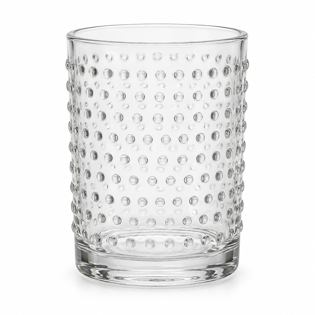 One clear embossed dot drinking glass stands alone against a pure white background.