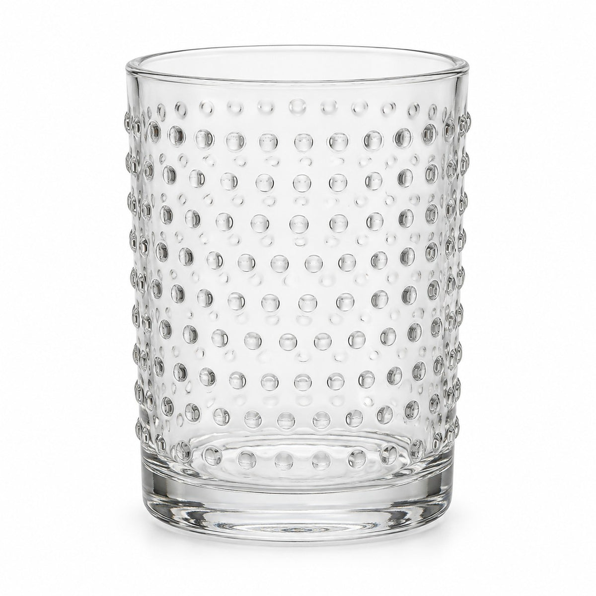 One clear embossed dot drinking glass stands alone against a pure white background.