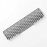A gray silicone dish drying rack with a slotted, ribbed design, shown diagonally on a clean white background.