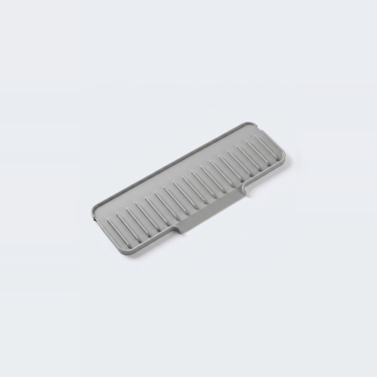 A gray silicone kitchen utensil, specifically a draining rack or strainer with parallel slotted channels, shown on a clean light gray background.