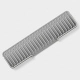 A gray plastic kitchen utensil or organizer tray with multiple parallel slots, shown on a clean light gray background.