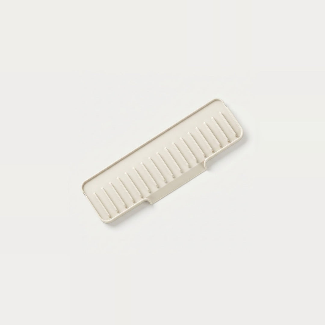 A rectangular plastic organizer tray with a slotted, ribbed design, shown at an angle on a clean, solid off-white background.