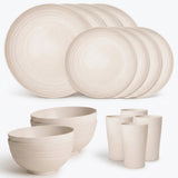 A coordinated ceramic dinnerware set in a warm off-white or cream tone, including multiple round plates, bowls, and cups, arranged on a clean white background.