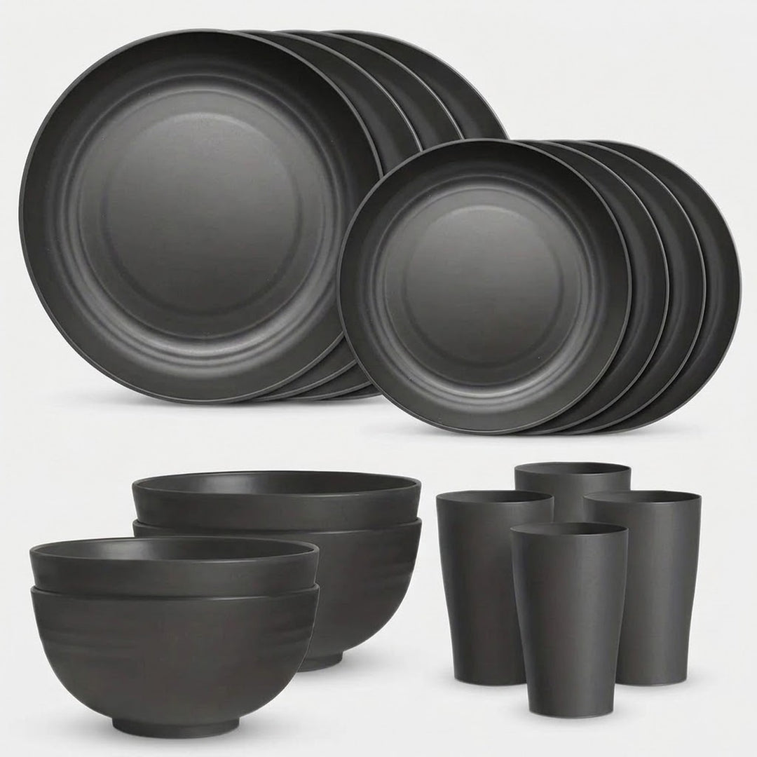 A matte black dinnerware set including plates, bowls, cups, and tumblers, arranged on a light gray background.