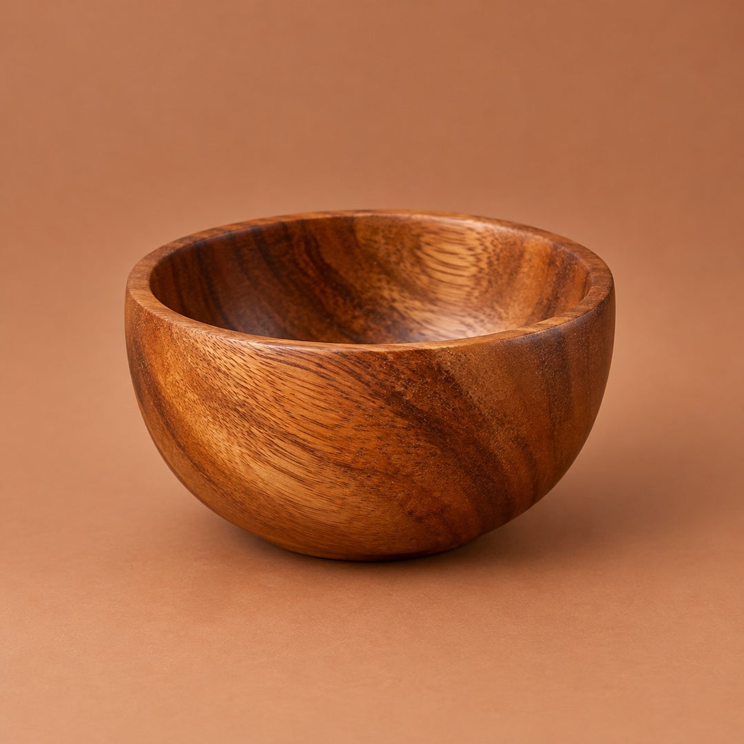 Small 225 ml acacia wood salad bowl centered on a warm tinted studio backdrop.