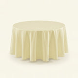 A round tablecloth in a soft cream or ivory color, draped elegantly over a circular table against a solid, light off-white background.