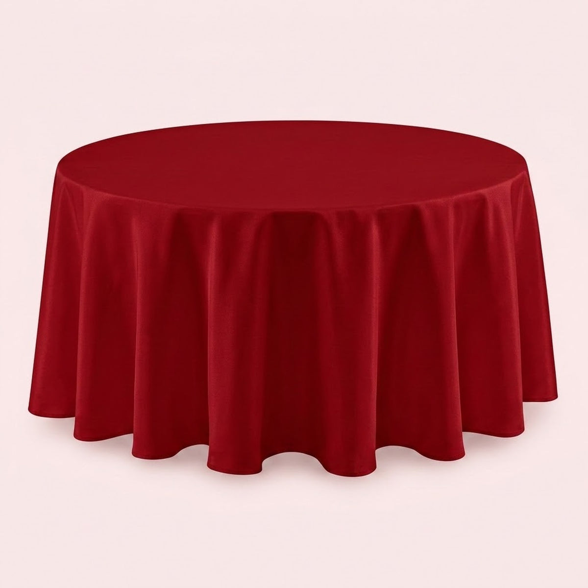 A round red tablecloth draped over a round table, shown against a plain light pink background.