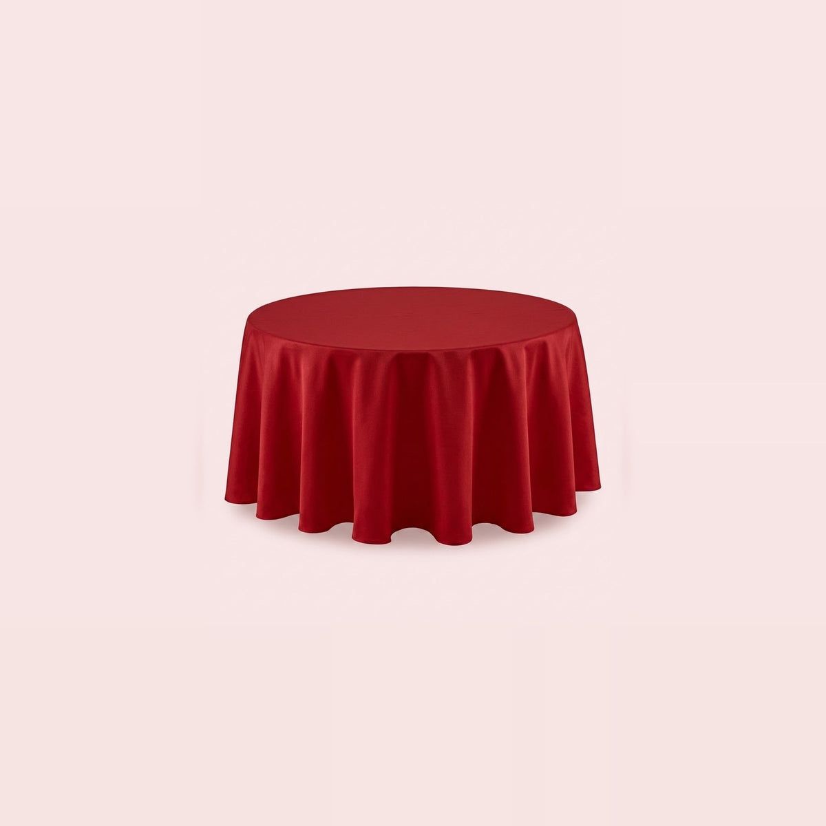 A round red tablecloth draped over a circular table, shown against a solid pale pink background.