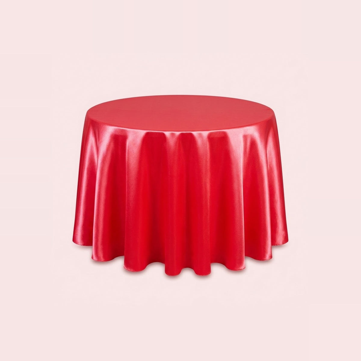 A round red tablecloth with a glossy, satin-like finish, draped over a round table against a solid pale pink background.