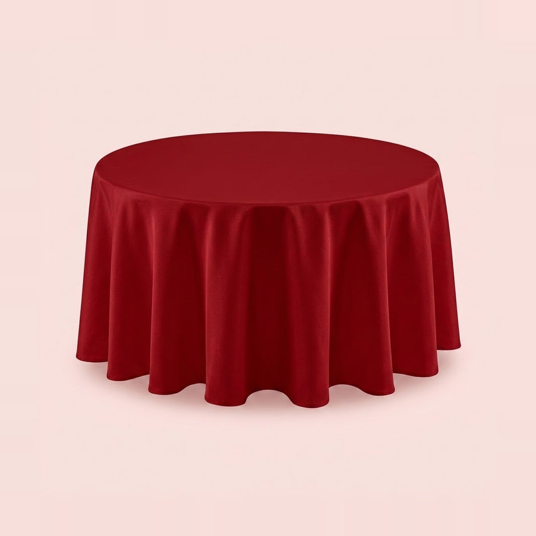 A round red tablecloth draped over a circular table, shown against a solid pale pink background.