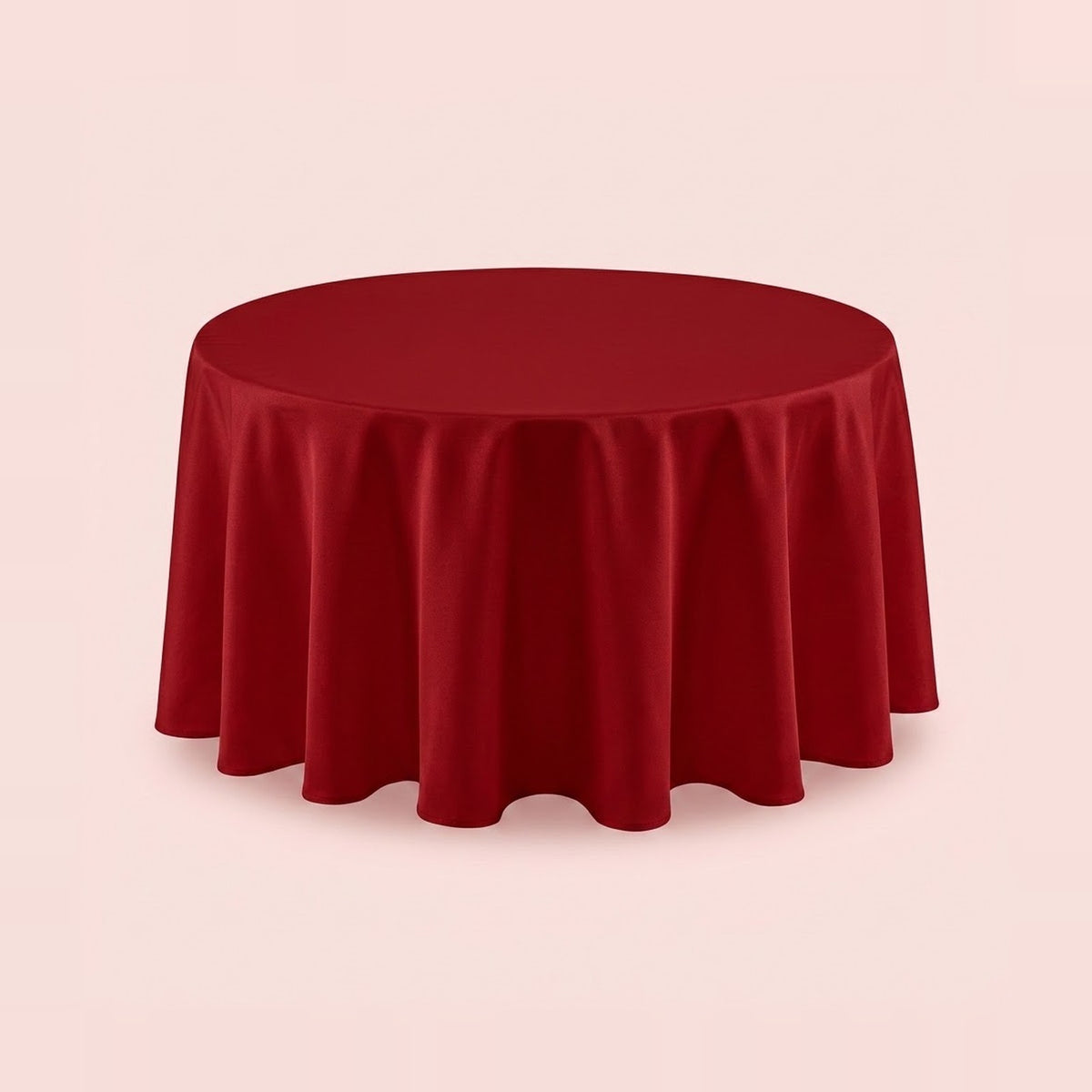 A round red tablecloth draped over a circular table, shown against a solid pale pink background.