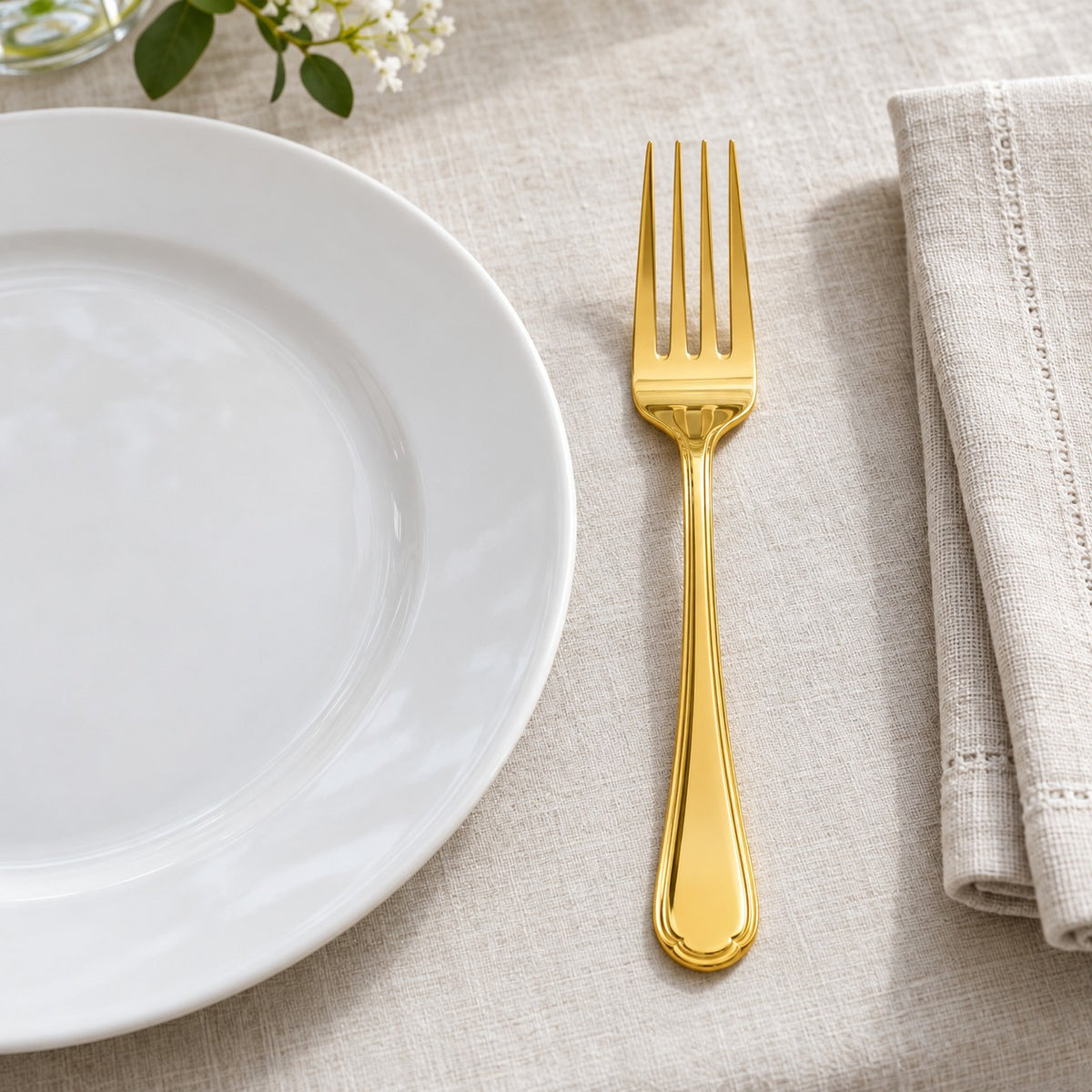 A gold disposable fork beside a dinner plate shows its full table setting scale.