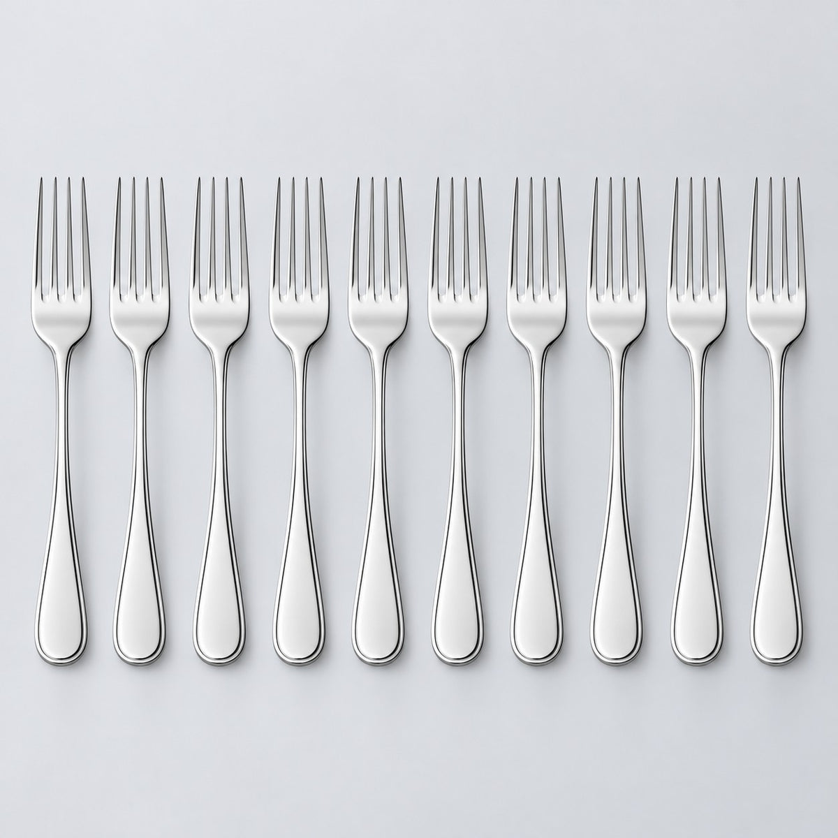Ten silver disposable forks stand in a row against a light silver studio background.