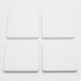 Four square white coasters arranged in a 2x2 grid on a plain white background.