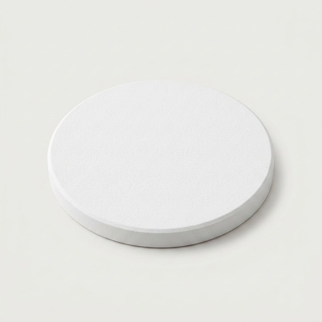 A minimalist white circular coaster or tray with a textured top surface and a smooth, slightly darker gray-white rim, shown on a light off-white background.