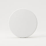 A plain white circular coaster or tile standing upright on a light gray surface against a light gray background.