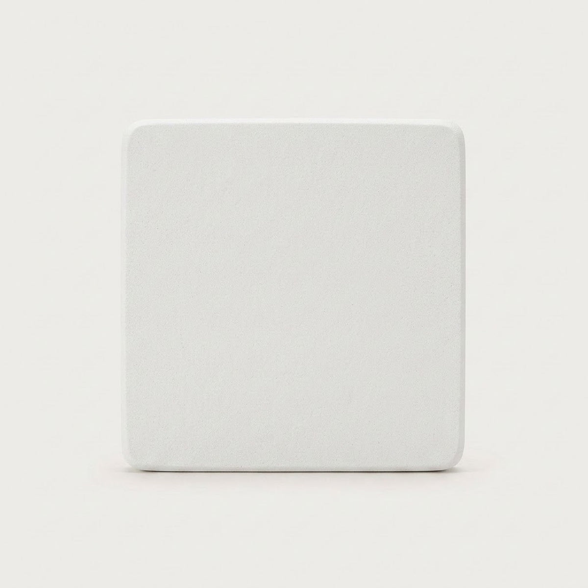 A square white coaster with rounded corners, shown from a top-down view on a light gray background.
