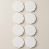 Six plain white circular discs arranged in two vertical columns on a light beige background.
