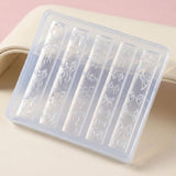 A translucent plastic nail stamping tray with six vertical slots, each featuring an embossed bow design, displayed on a light beige surface with a soft pink background.