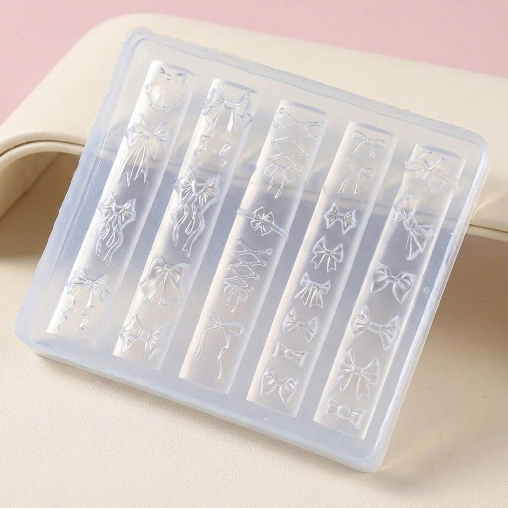 A translucent plastic nail stamping tray with six vertical slots, each featuring an embossed bow design, displayed on a light beige surface with a soft pink background.