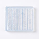 A translucent silicone mold tray with six vertical cavities, each featuring embossed bow and ribbon patterns, shown on a plain white background.