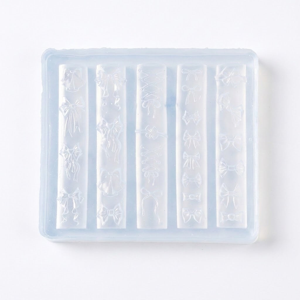 A translucent silicone mold tray with six vertical cavities, each featuring embossed bow and ribbon patterns, shown on a plain white background.
