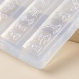 A close-up of a translucent plastic mold tray with embossed bow-shaped cavities, photographed on a light beige surface.