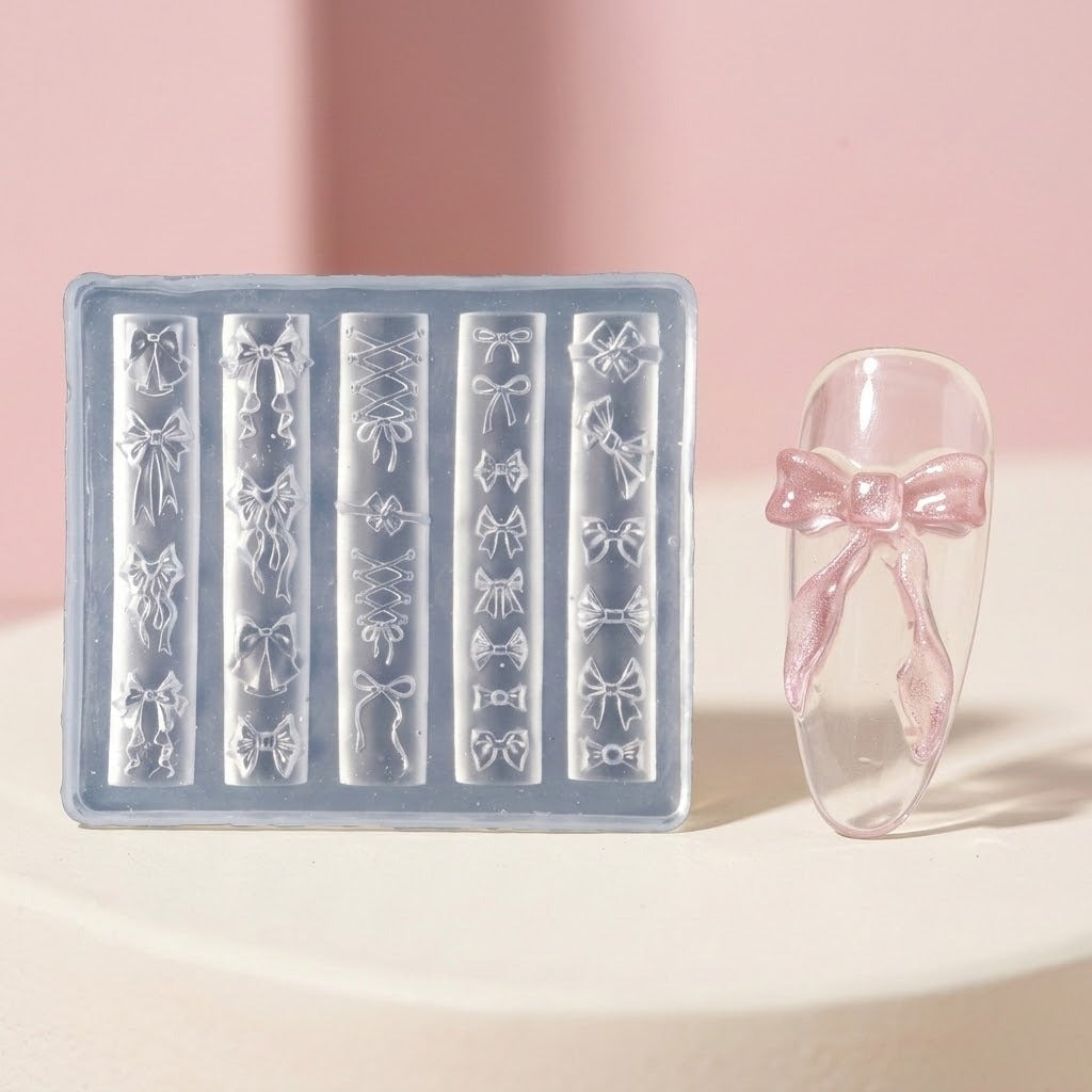 A clear plastic nail stamping mold with multiple rows of bow-shaped cavities, shown next to a clear artificial nail tip decorated with a pink bow, on a soft pink and cream background.