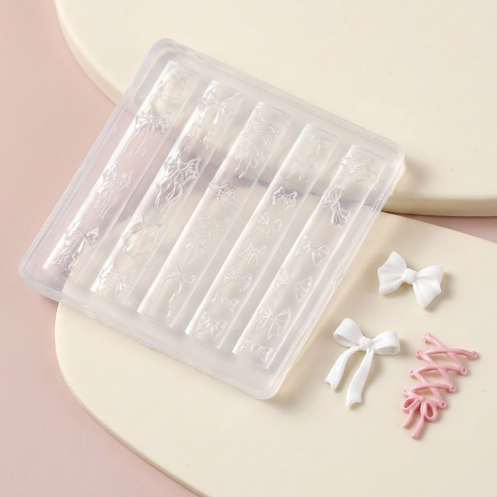 A clear plastic nail art stamping tray with floral and bow designs, shown on a beige and pink background with small white and pink ribbon sample pieces beside it.