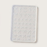 A rectangular translucent silicone mold with rows of small bow-shaped cavities, shown on a plain light background.