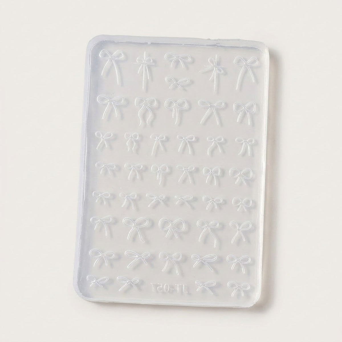 A rectangular translucent silicone mold with rows of small bow-shaped cavities, shown on a plain light background.